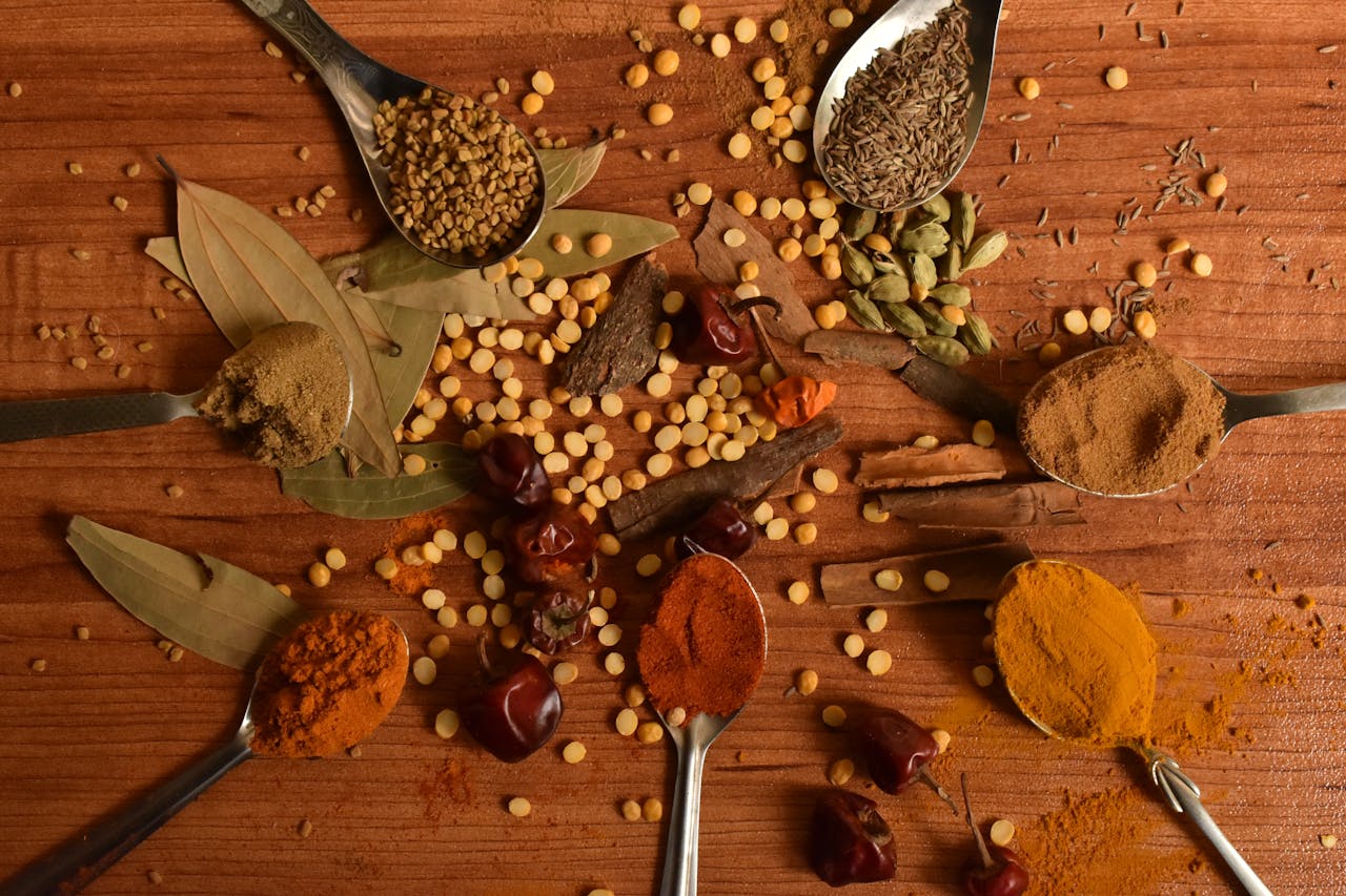 A vibrant display of various Indian spices arranged creatively on a wooden table.
